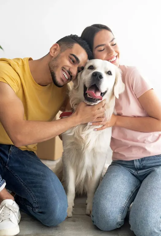 A man and woman sitting on the ground with their dog.