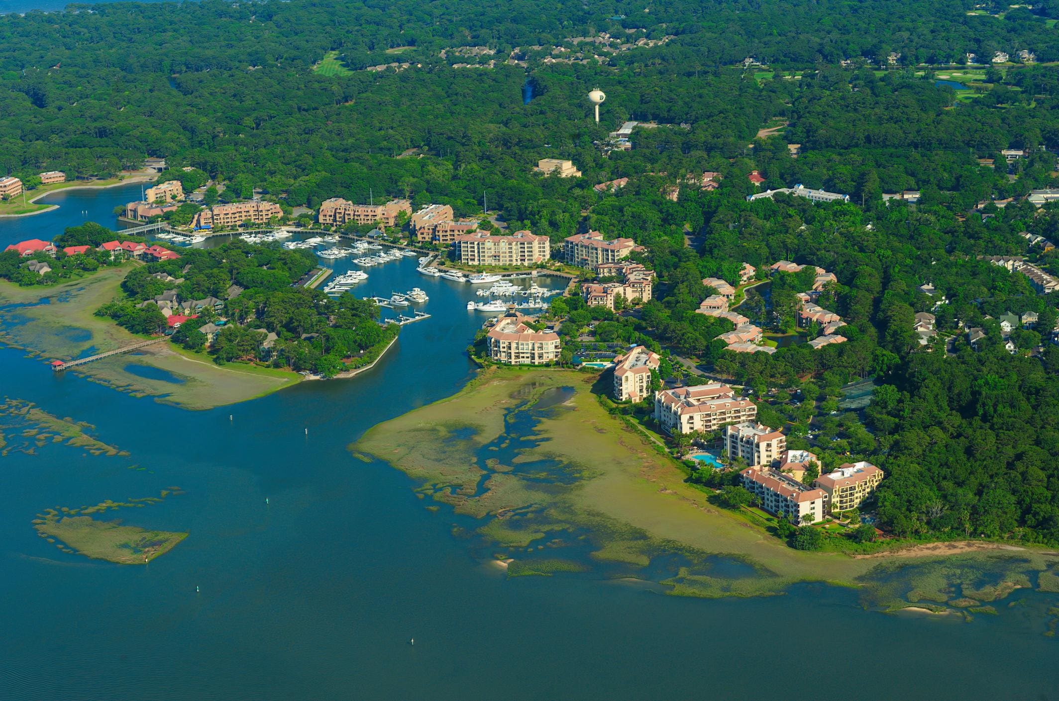 A view of the water from above shows many houses and boats.